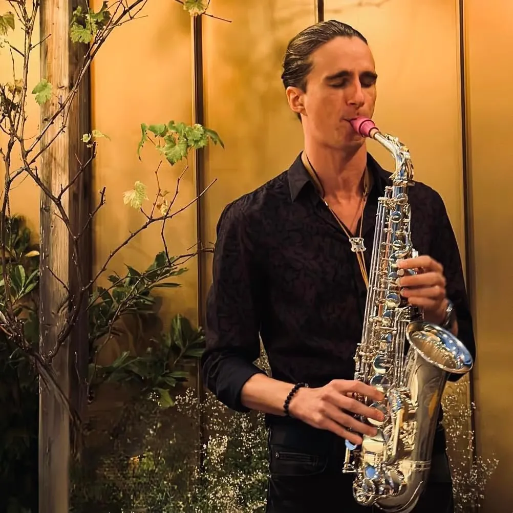 Saxophonist mit silbernem Saxophon in stimmungsvoller Lounge-Atmosphäre
